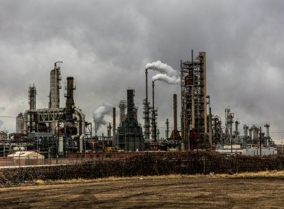 Industrial refinery complex with smoke stacks under cloudy sky, highlighting environmental impact and industrialisation