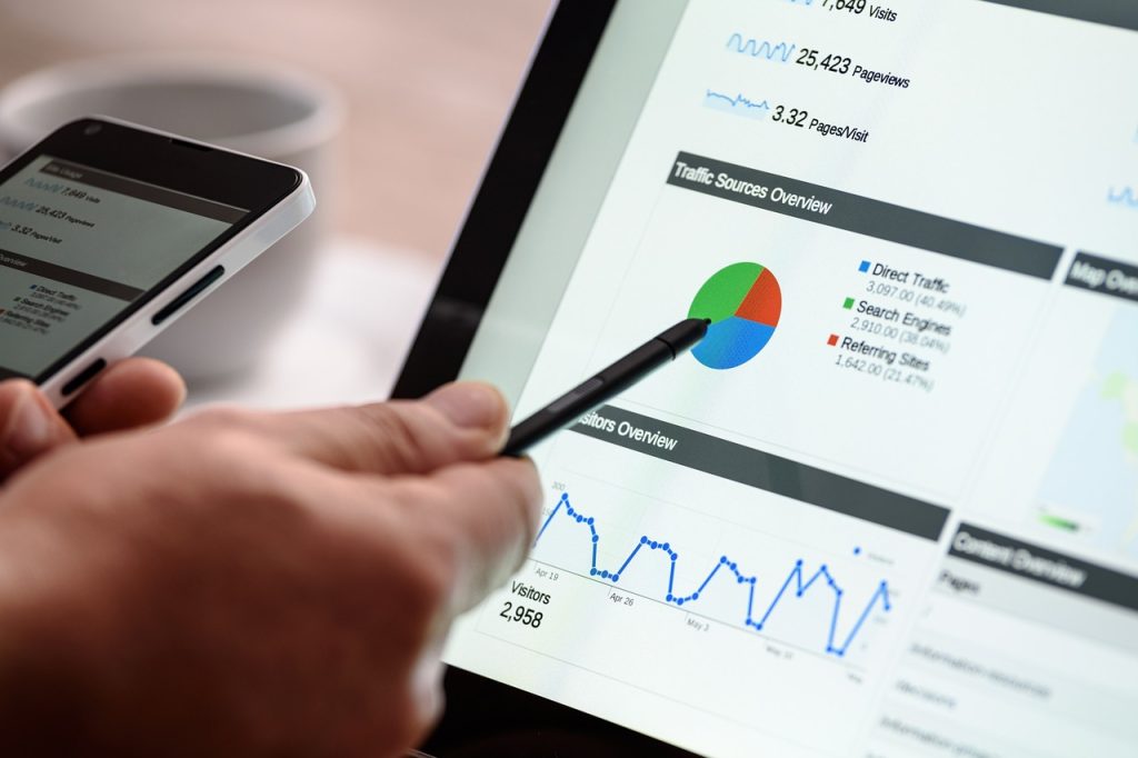 Person analysing digital marketing data on tablet displaying traffic sources and analytics graphs
